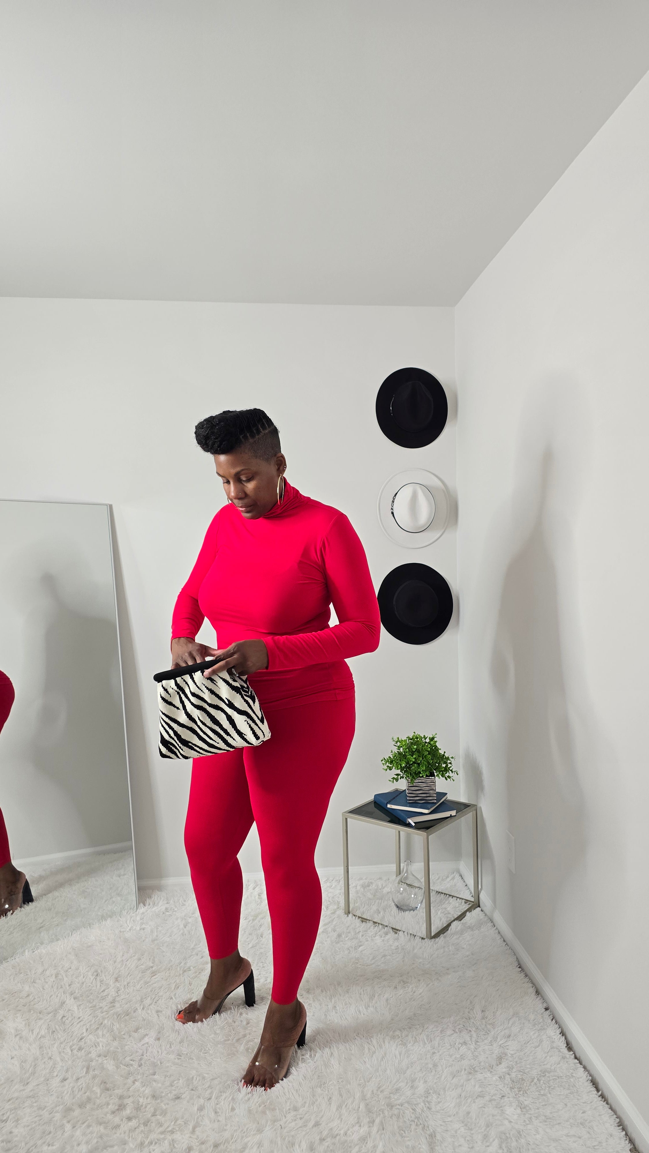 Person wearing a red outfit with zebra print shoes in a minimalistic room.