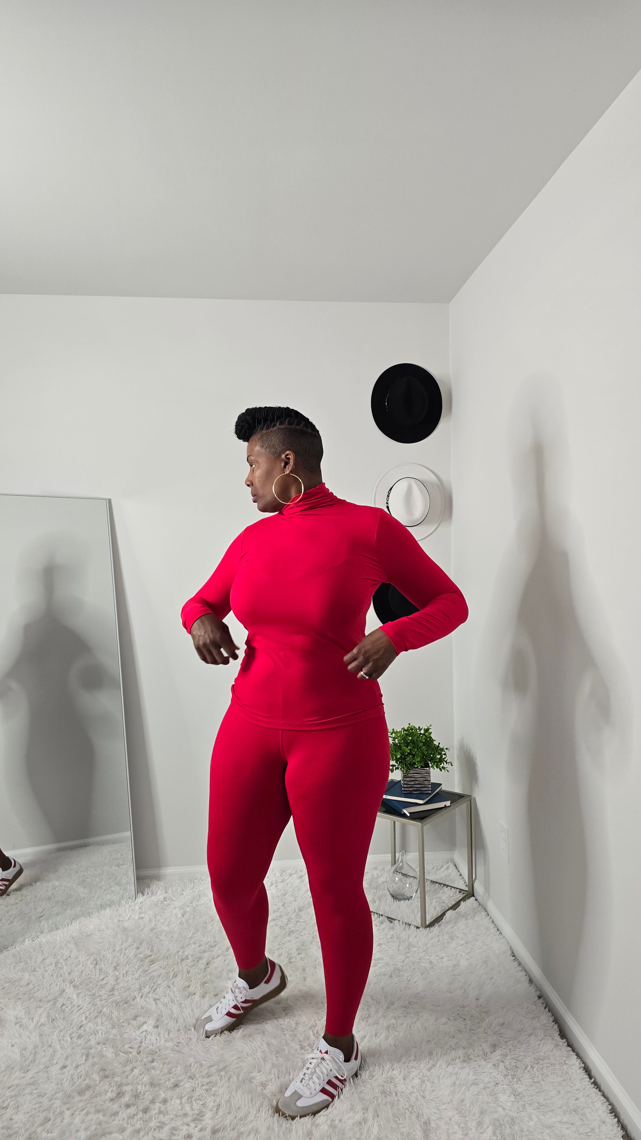 Person wearing a red outfit standing in a room with white walls and a gray carpet.
