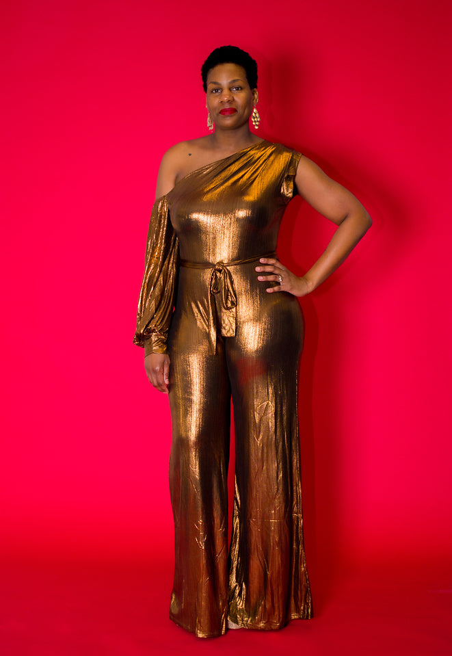 Shimmery Bronze One-Shoulder Jumpsuit  Drape yourself in elegance with our Shimmery Bronze One-Shoulder Jumpsuit, a modern masterpiece that exudes glamour and sophistication. Crafted from semi-stretch fabric, this jumpsuit ensures comfort while accentuating the body's curves. The one-shoulder design and long sleeves add a touch of refinement, making it perfect for special occasions. The wide legs contribute to a timelessly elegant silhouette, offering versatility for various events.