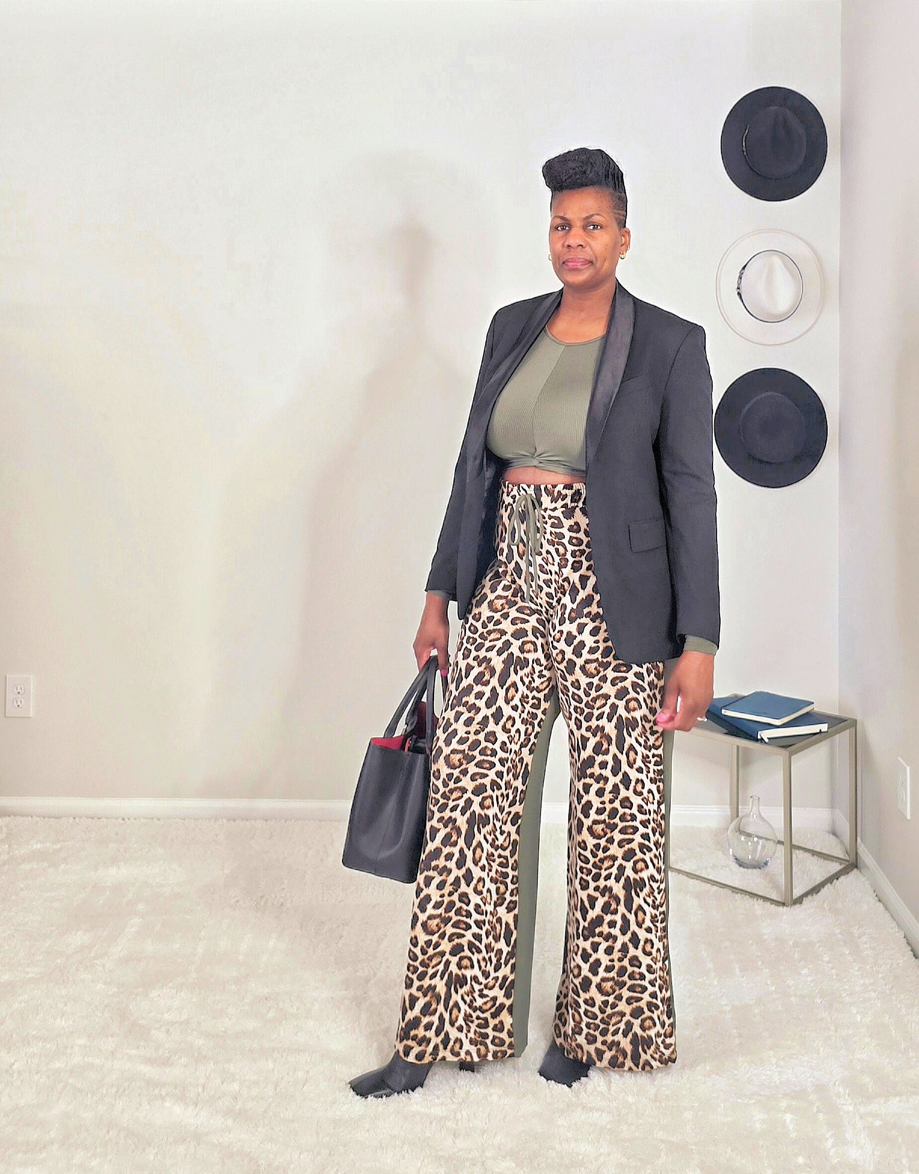 Person wearing a black blazer and leopard print pants in an indoor setting.