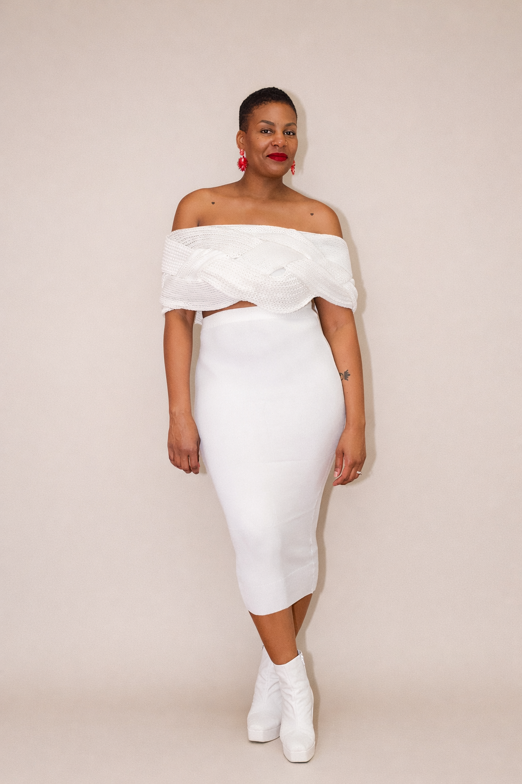 Woman wearing a white off-shoulder top and skirt set against a plain background