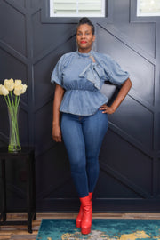 Denim Blue Short Sleeve Top from Tosh`E Boutique, featuring a cinched waist for a flattering fit and a bow tie neck for a touch of playful sophistication. In a versatile denim blue hue, this top offers a blend of casual charm and feminine elegance, perfect for relaxed outings or casual gatherings.