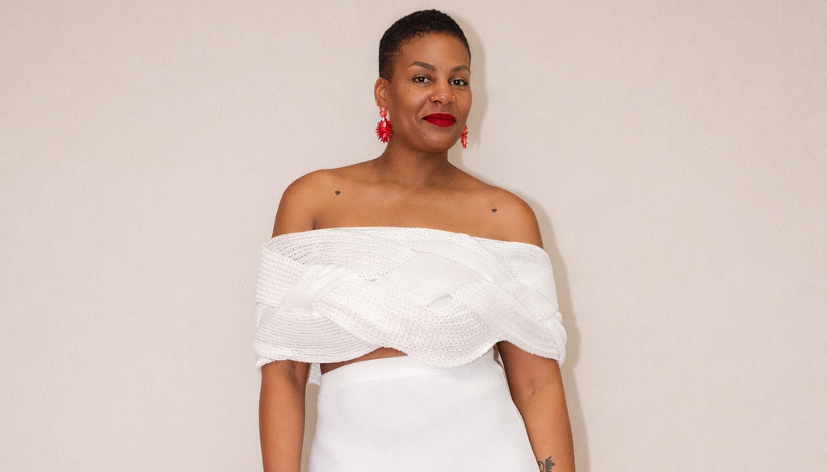 Woman wearing a white off-shoulder dress against a plain background