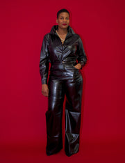 Two-piece faux leather pant set in black, featuring a button-down shirt with long sleeves and high-waisted wide-leg pants with pockets. A bold and edgy outfit for a confident fashion statement