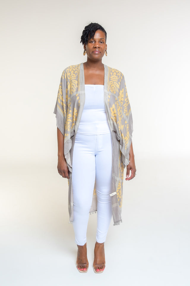 Available in Grey Damask Print  Elevate your style with our beautifully crafted kimono, available in a stunning denim damask print. This versatile piece is perfect for any occasion, blending elegance with casual charm.  Key Features:  Split Angel Sleeves: Add a touch of sophistication and flowy elegance with our unique split angel sleeves. Mini Pom Pom Accent: Delicate mini pom pom accents along the edges provide a playful yet chic detail. 100% Viscose: 