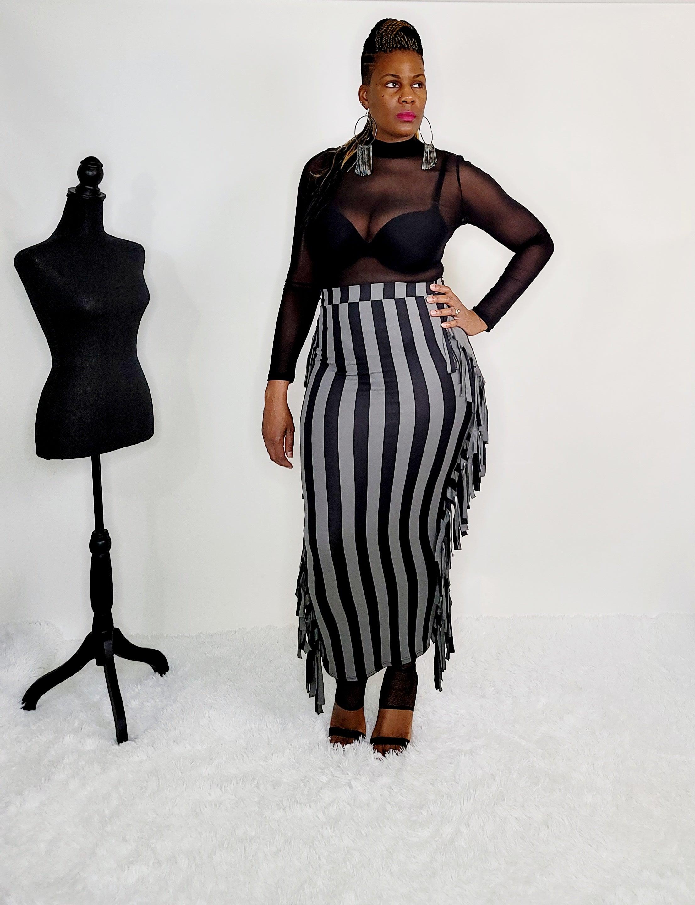 Model wearing a chic Grey/Black Maxi Skirt in size large, featuring stylish fringe sides and a flattering high-waisted fit. This versatile long skirt, made from a polyester and spandex blend, showcases a trendy stripe pattern. Perfect for stylish women's fashion, offering both comfort and effortless style